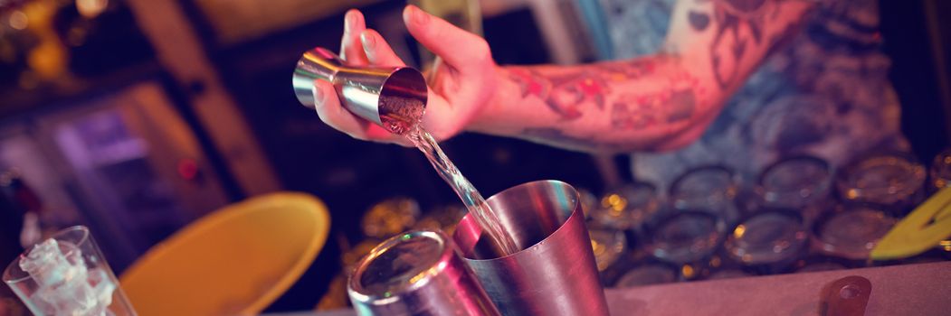 Bartender preparing a drink at counter in bar