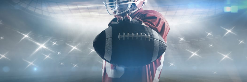 Young American football player standing in rugby helmet and holding rugby ball