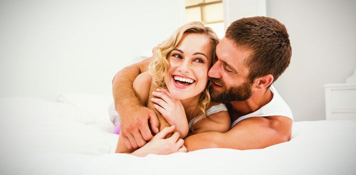 Happy young couple embracing on bed in bedroom