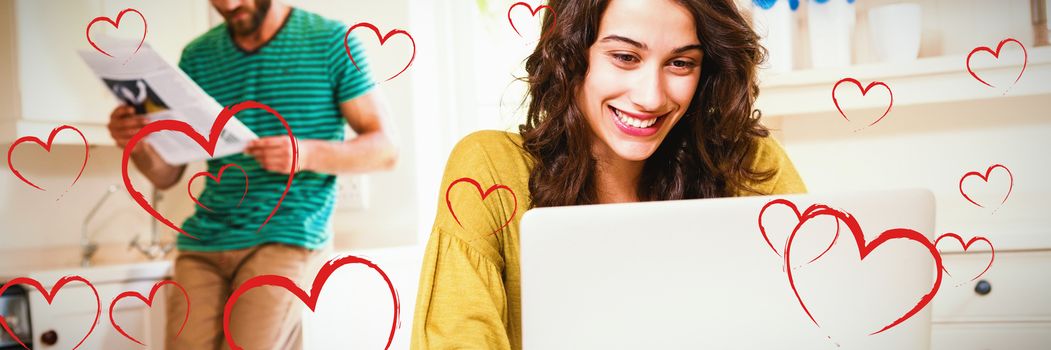 Red Hearts against woman using laptop while man reading newspaper in background