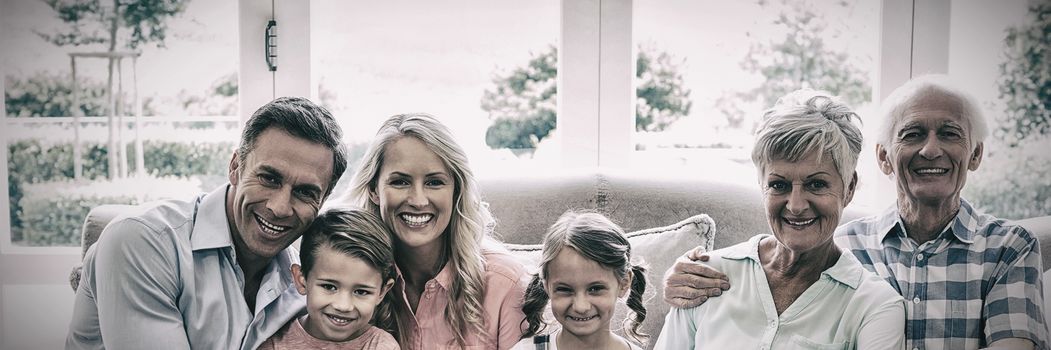 Multi generation family sitting on sofa in living room at home