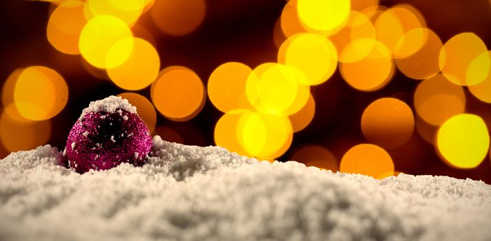 Christmas balls with an electric garland while snowing against unfocused christmas light