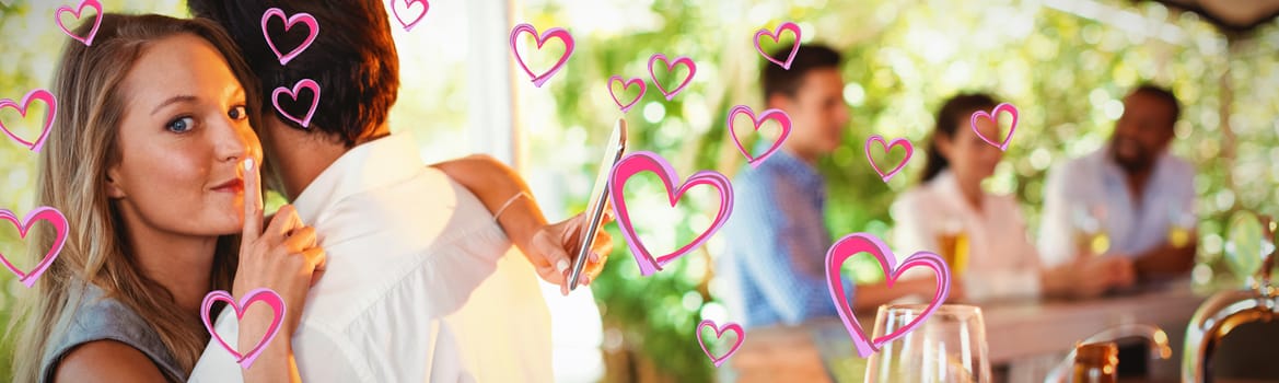 Red Hearts against couple embracing while using mobile phone