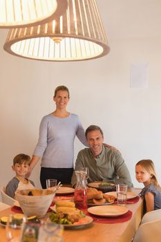 Portrait of happy family sitting on dining table at home