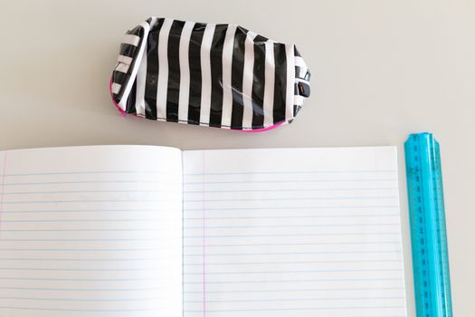 Close-up of notebook, ruler and pencil case on the desk in school