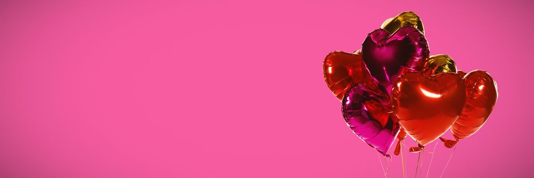 Multicoloured heart shape balloons against pink background