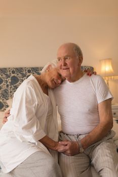 Front view of happy senior couple embracing each other relaxing in bedroom at home