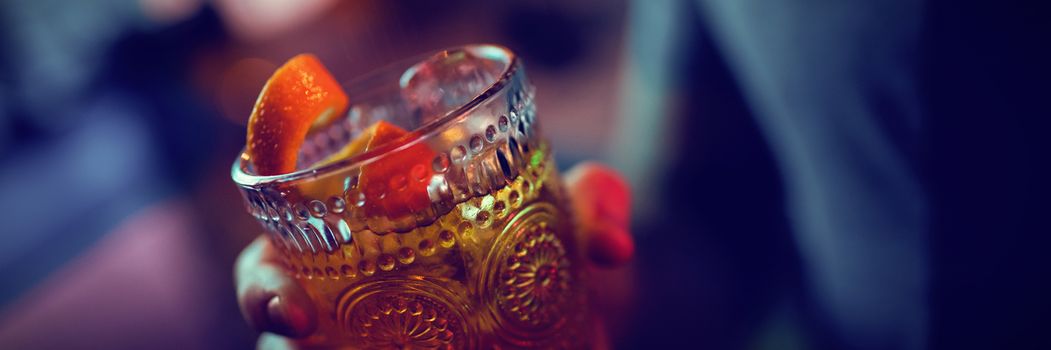 Man holding a glass of orange cocktail in bar