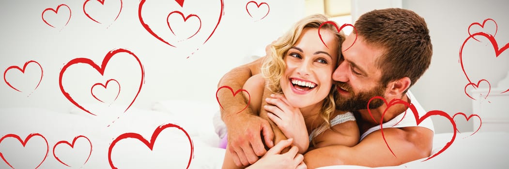 Red Hearts against young couple embracing on bed