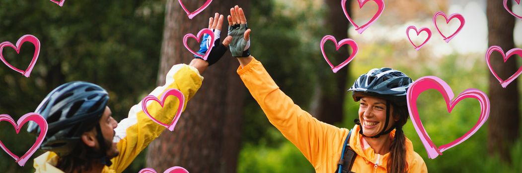 Red Hearts against biker couple giving high five to each other in countryside