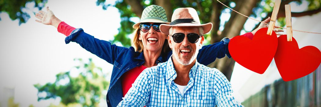 Hearts hanging on line against couple enjoying while riding bicycle