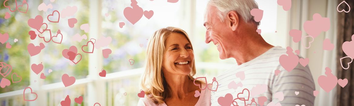 Valentines heart design against happy senior couple interacting with each other in balcony