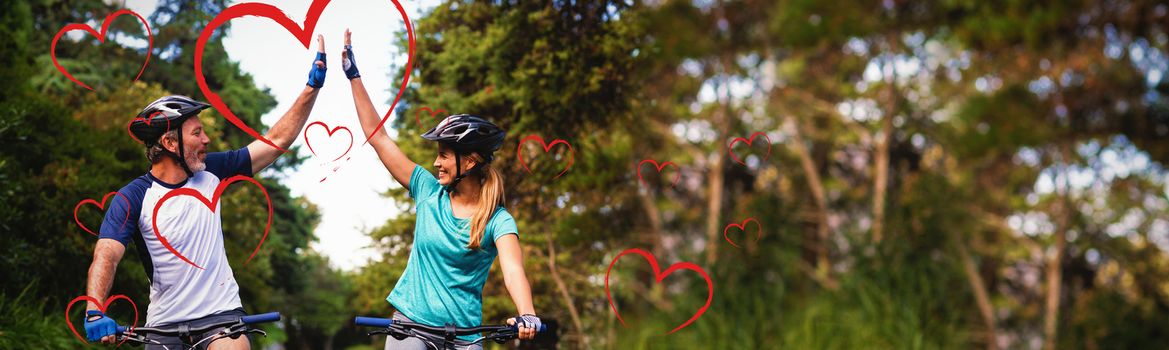 Red Hearts against athletic couple giving high five while riding bicycle on the road