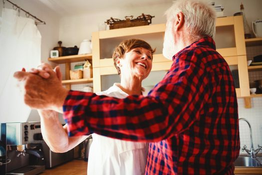 Romantic senior couple dancing together in kitchen
