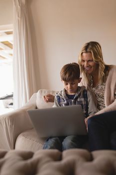 Front view of mother helping her son use laptop in stylishly decorated living room at home