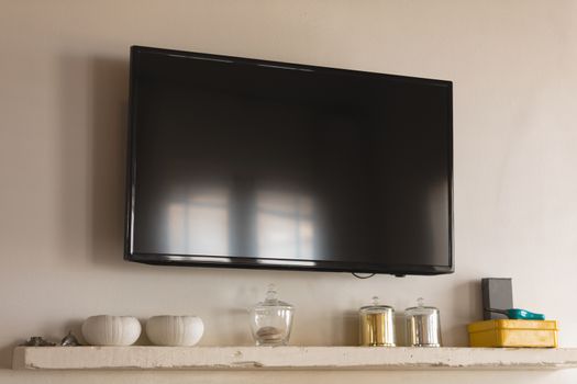 Modern LED television fixed on the wall above bowl and box at home