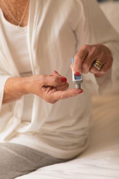 Mid section of senior woman applying cream on her finger at home