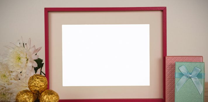 Empty photo frame, flower, chocolates and gift boxes on a table