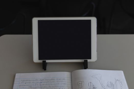 Close-up of digital tablet and notebook with notebook on desk in classroom