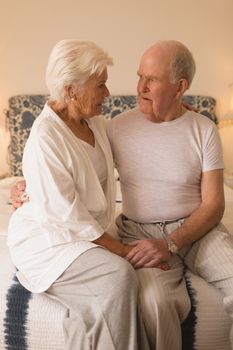 Front view of senior couple looking at each other on bed in the bedroom at home