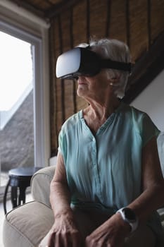 Front view of a senior woman using virtual reality headset in living room at home