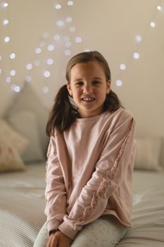 Portrait of innocent girl sitting in bedroom at home