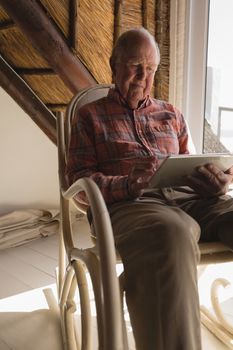 Front view of a senior man using laptop on a rocking chair in living room at home