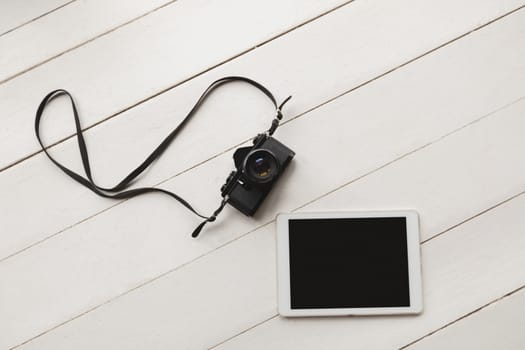 Overhead view of digital tablet and camera placed on the floor at home