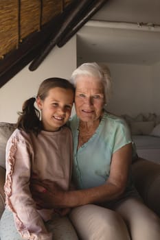Portrait of grandmother and granddaughter relaxing together in living room at home