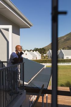 Side view of a handsome senior African American man having a mug of coffee on the balcony at home