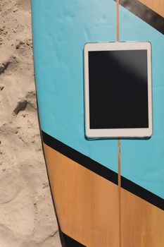 Close-up of digital tablet on surfboard at beach in the sunshine