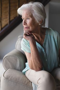 Front view of a thoughtful senior woman relaxing in living room at home