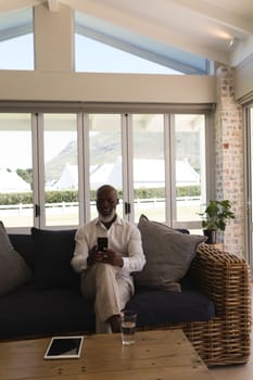 Front view of active senior man using mobile phone in living room at home