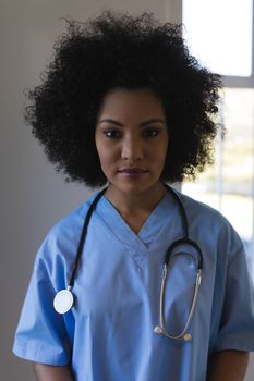 Portrait of beautiful young African American female doctor with stethoscope standing at home