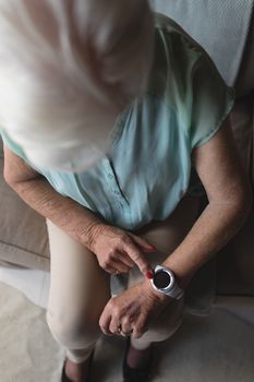 High angle view of a senior woman checking time on her wristwatch at home
