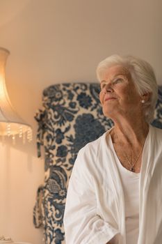 Front view of a senior woman looking up in her bedroom at home