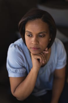 High angle view of thoughtful woman relaxing on sofa in living room at home