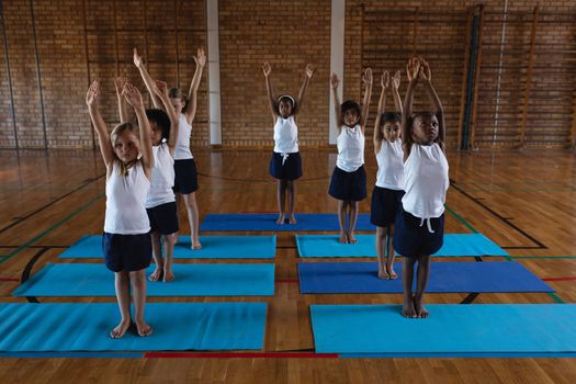 Front view of schoolkids doing yoga on a yoga mat in school