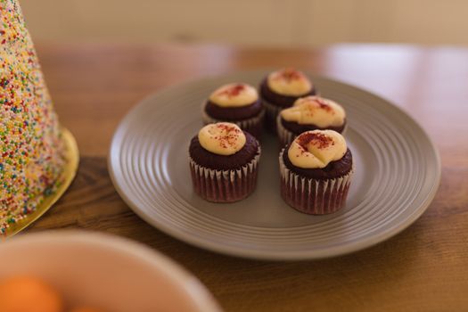 Close-up of chocolate cupcakes with topping on a plate on a wooden table at home