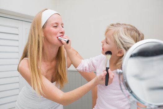 Happy mother and daughter playing with make up at home in the bathroom