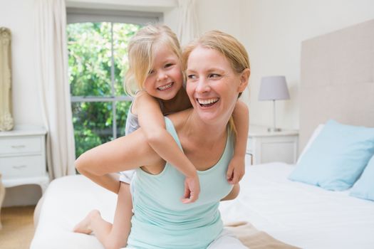 Cute little girl and mother on bed at home in the bedroom