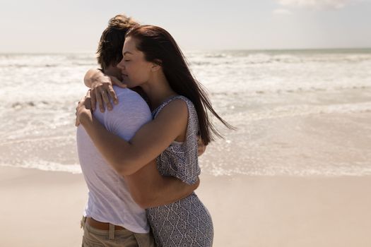 Side view of romantic young couple embracing each other on beach in the sunshine