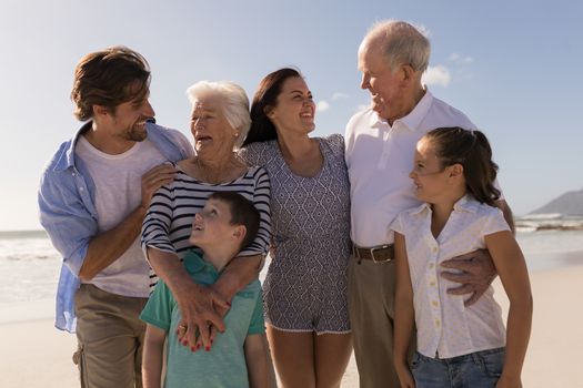 Front view of happy multi-generation family looking each other on beach in the sunshine