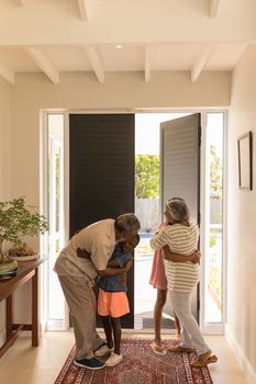 Front view of happy African American grandparents cuddling their grandchildren at home