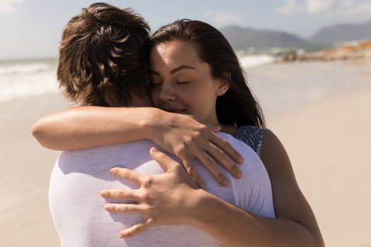 Closeup of a romantic young couple embracing each other on beach in the sunshine