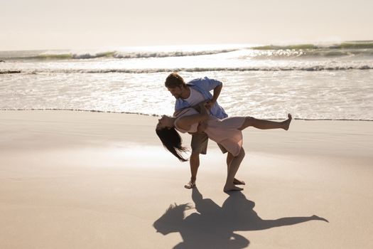 Front view of romantic young couple dancing on beach in the sunshine