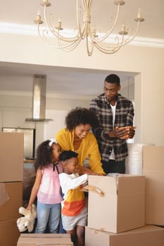 Front view of happy African American parents with their children packing their belongings in living room at home