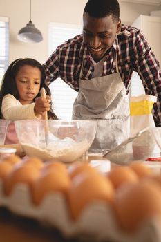 Front view of African American father and daughter baking cookies in kitchen at home