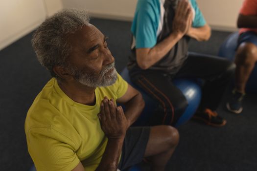 High angle view of active senior men performing yoga doing exercice ball at home