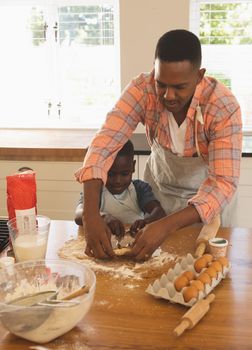 Front view of African American father and son baking cookies in kitchen at home